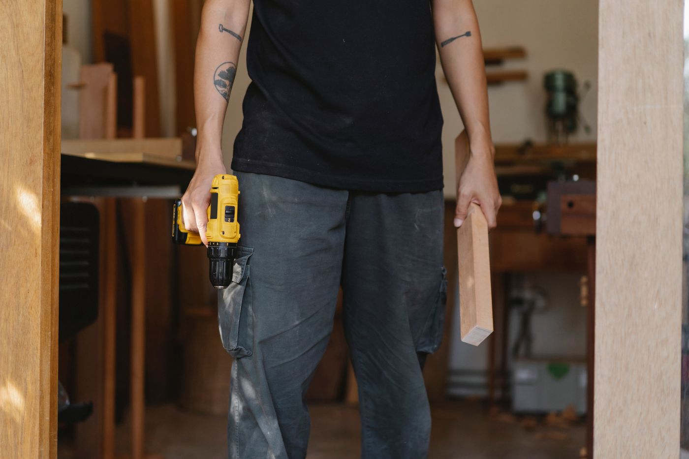 Carpenter holding a cordless drill in a woodworking workshop
