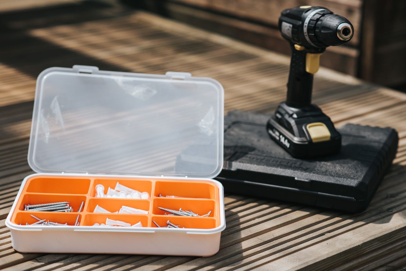 Cordless electric screwdriver placed near a screw set on a wooden surface