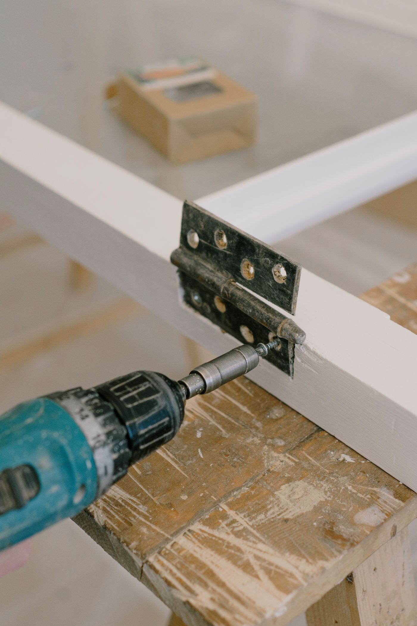 Electric screwdriver fastening a metal hinge during a practical tool test